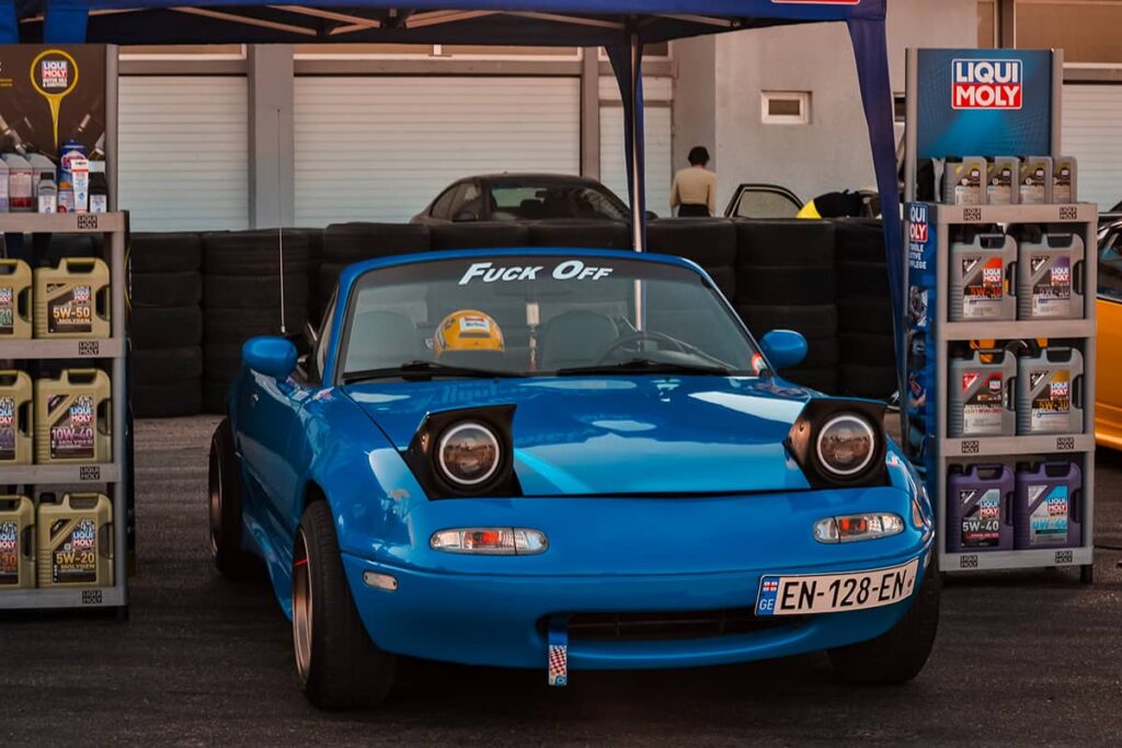 Open Top Mazda Miata NA roadster in the booth at the race track